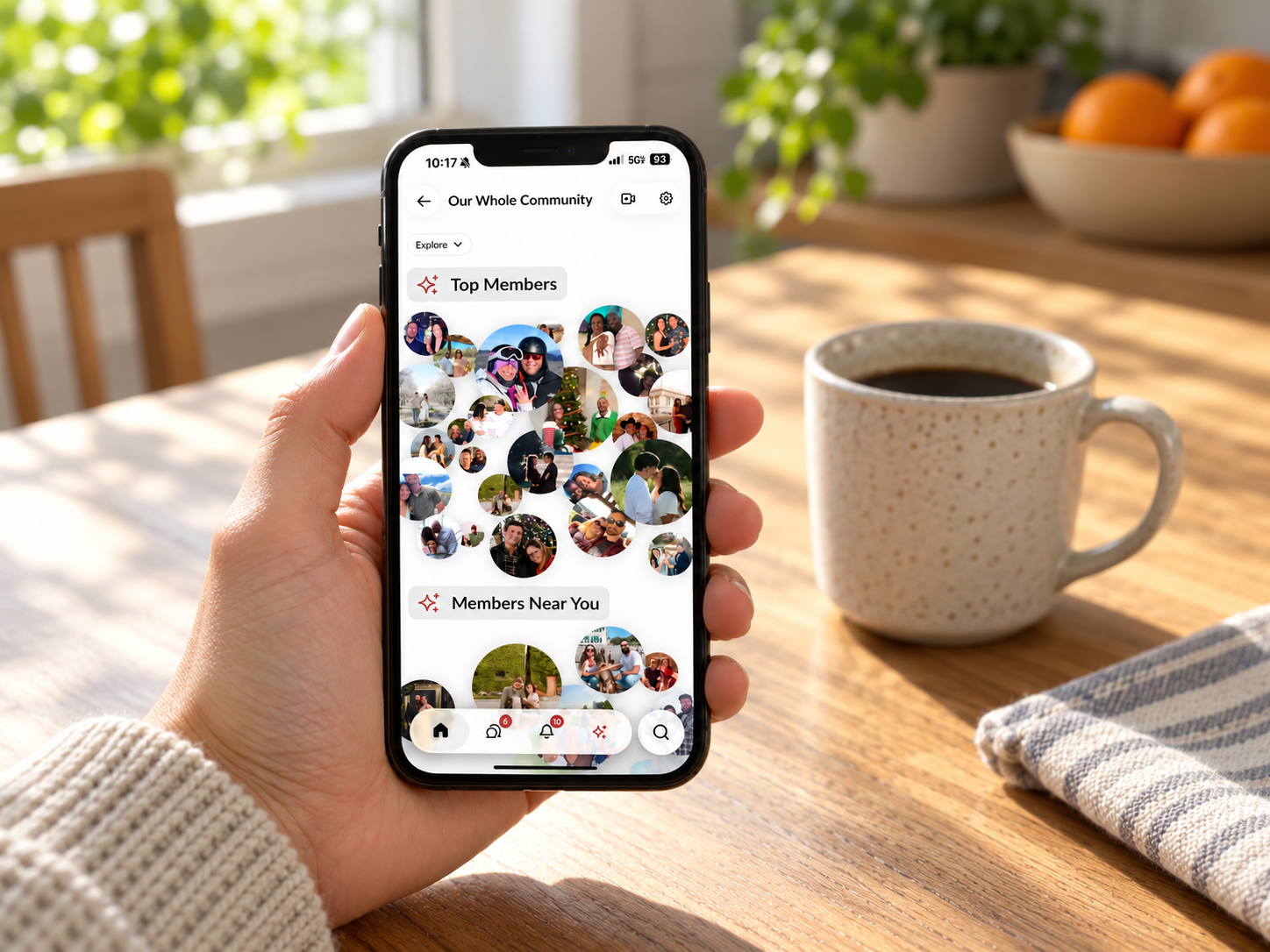 A married member holding a phone at a wooden table, browsing community photos of members near them on the Marriage Every Day app